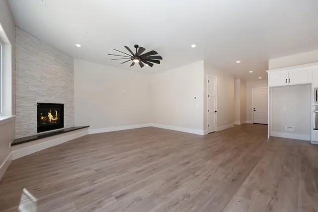a view of an empty room with wooden floor and a fireplace