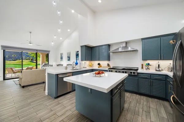 a kitchen with a stove a sink dishwasher and a refrigerator with wooden floor