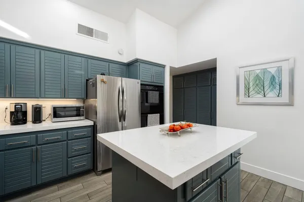 a kitchen that has a kitchen island wooden cabinets and refrigerator
