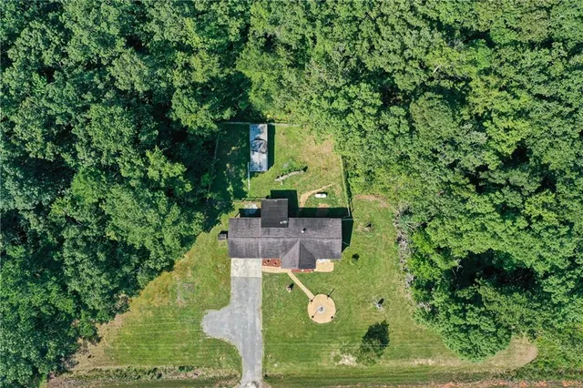 an aerial view of residential house with outdoor space and trees all around