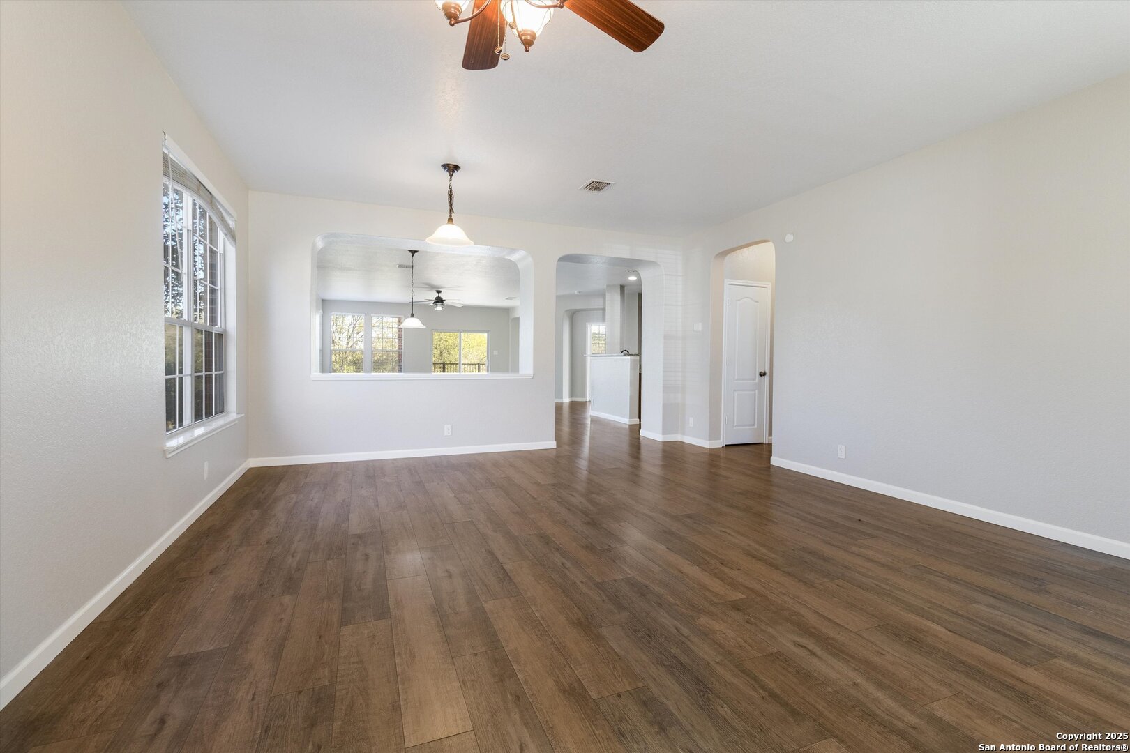 13506 Misty View San Antonio, TX 78245 - Photo 4 of 29 an empty room with wooden floor chandelier fan and windows