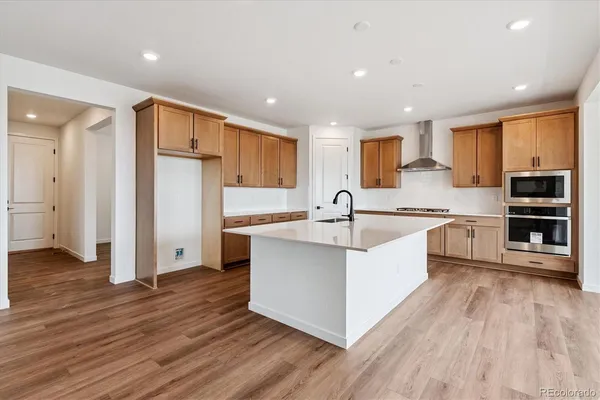 a large kitchen with stainless steel appliances a large counter top a stove a refrigerator and a sink