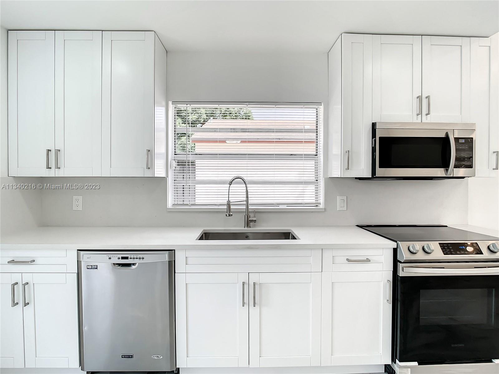 14031 Langley Place Davie, FL 33325 - Photo 2 of 27 a kitchen with stainless steel appliances white cabinets and a sink
