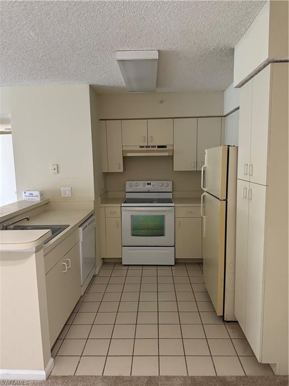 13631 Eagle Ridge Drive, Unit 226 Fort Myers, FL 33912 - Photo 3 of 19 a kitchen with granite countertop a refrigerator and a stove top oven