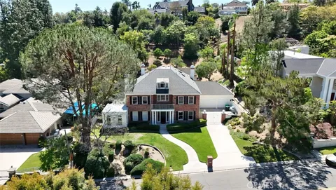 a aerial view of a house with swimming pool and large trees