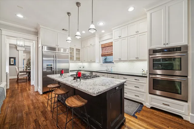 a kitchen with kitchen island a stove a counter space a sink and cabinets