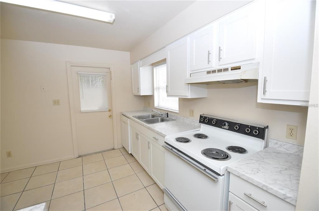 1434 East Fern Road, Unit 1434 Lakeland, FL 33801 - Photo 8 of 13 a white kitchen with a sink a stove and cabinets