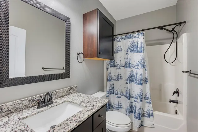 a bathroom with a granite countertop sink toilet a shower and a mirror
