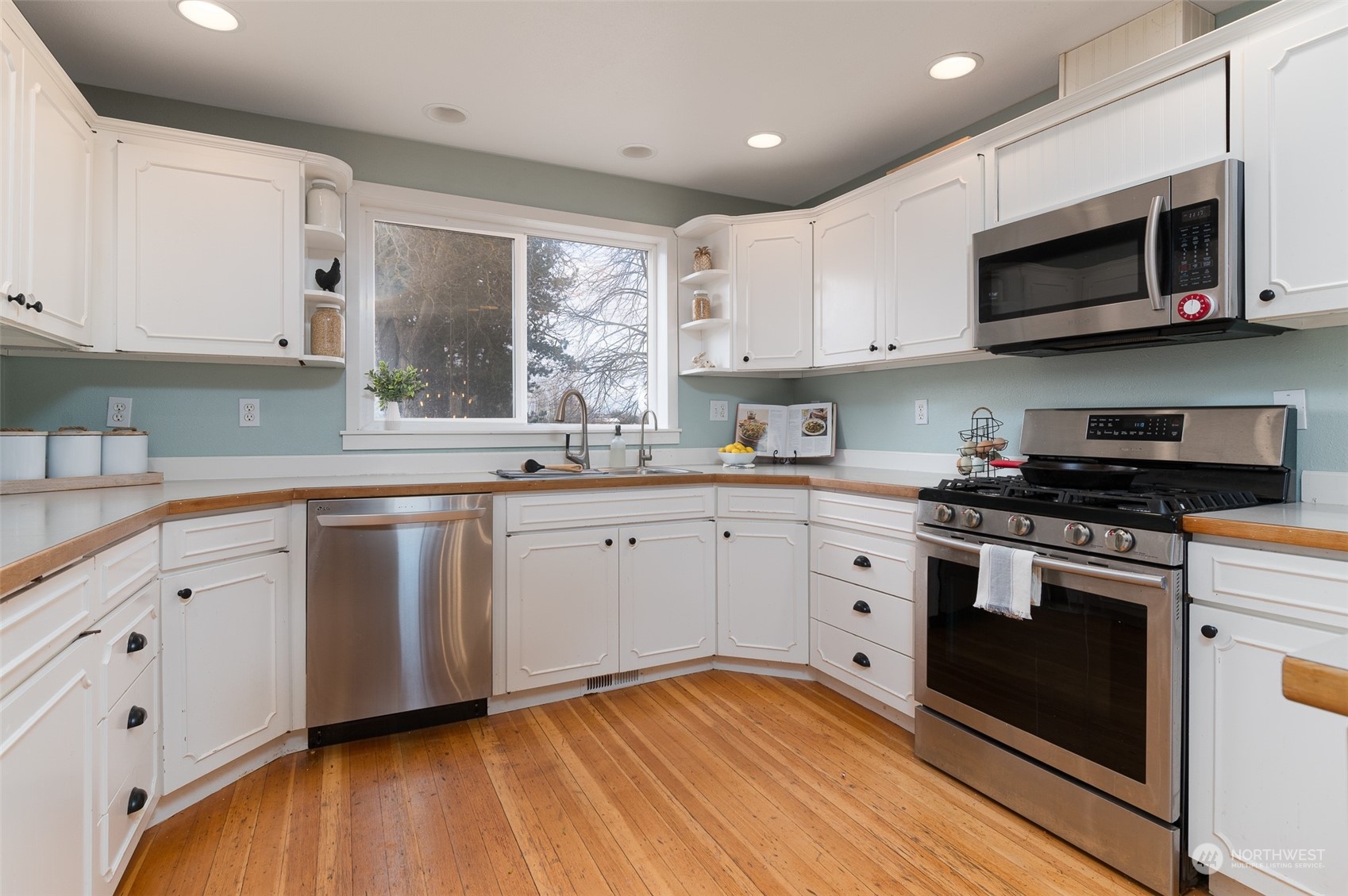 5757 Barr Road Ferndale, WA 98248 - Photo 11 of 40 a kitchen with stainless steel appliances granite countertop a sink a stove top oven a refrigerator with white cabinets and a wooden floor