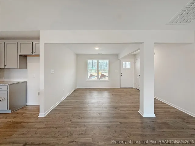 a view of an empty room with window and wooden floor