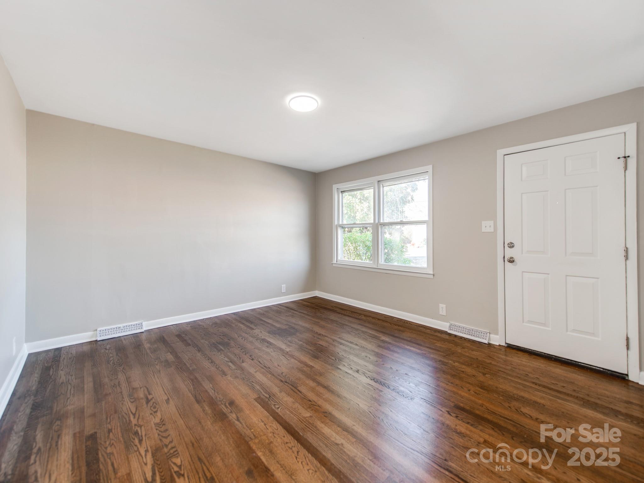 502 McConnell Street Clover, SC 29710 - Photo 5 of 25 an empty room with wooden floor and windows