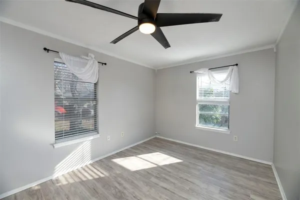 a view of an empty room with a window and wooden floor