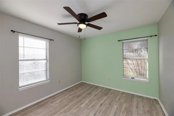 a view of an empty room with wooden floor and a window