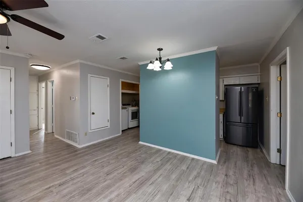 a view of a hallway with wooden floor and a kitchen