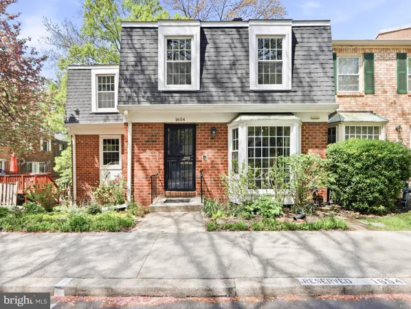 front view of a brick house with a yard and a car parked