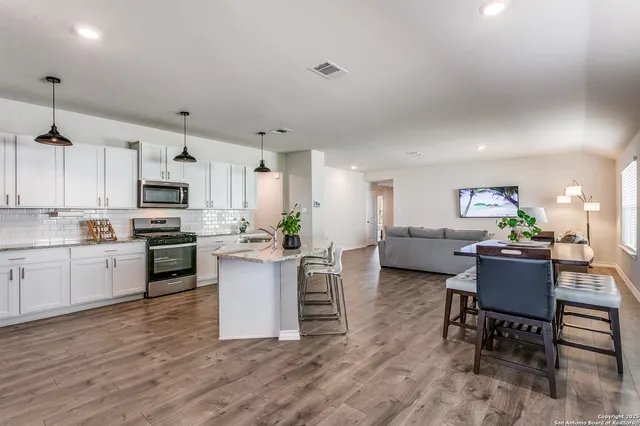 a kitchen with stainless steel appliances a stove a sink a oven a dining table and chairs