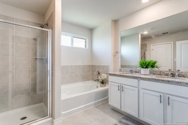 a bathroom with a granite countertop sink a mirror a bathtub and shower