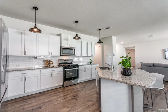 a kitchen with a refrigerator a stove a sink and white cabinets
