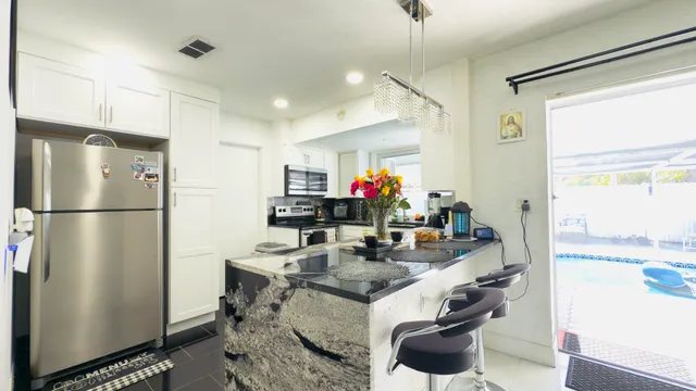 a kitchen with stainless steel appliances kitchen island granite countertop a sink and a refrigerator