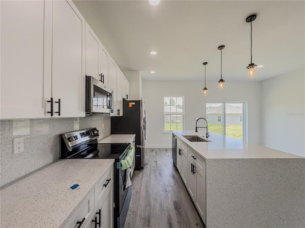 14245 Southwest 28th Court Ocala, FL 34473 - Photo 33 of 85 a kitchen with stainless steel appliances a stove a sink a refrigerator a center island and wooden floor