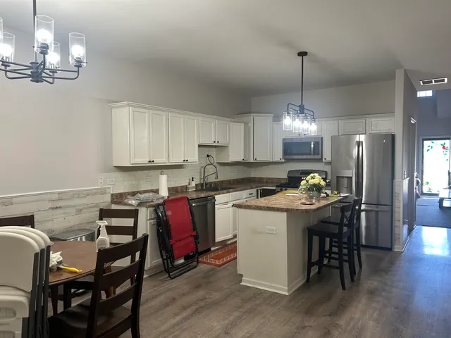 a kitchen with kitchen island a dining table chairs and cabinets