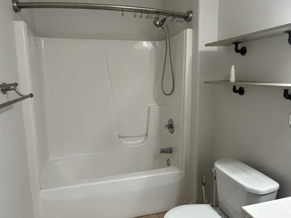 a white toilet sitting next to a bath tub and a shower
