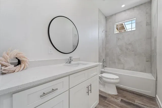 a bathroom with a granite countertop toilet a sink and a mirror