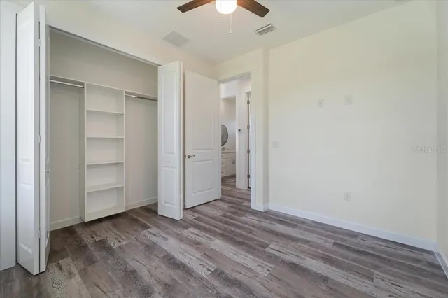 an empty room with closet and a chandelier fan