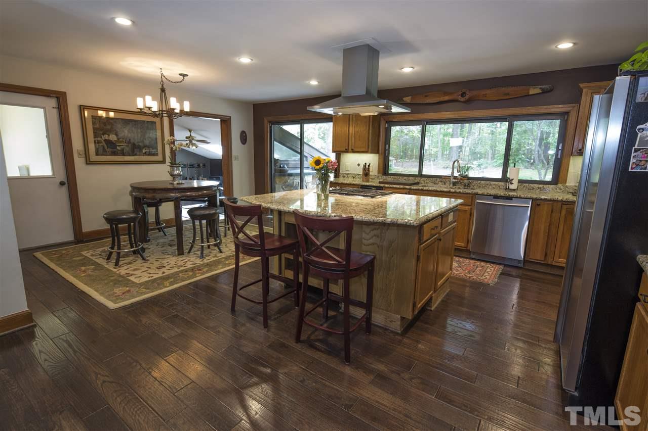 813 Thatcher Way Raleigh, NC 27615 - Photo 8 of 25 a dining hall with stainless steel appliances granite countertop a stove a refrigerator a kitchen island a couches and couches with wooden floor