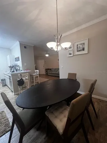 a dining room with wooden floor a chandelier a wooden table and chairs