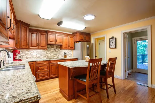 a kitchen with stainless steel appliances granite countertop wooden cabinets a dining table and chairs