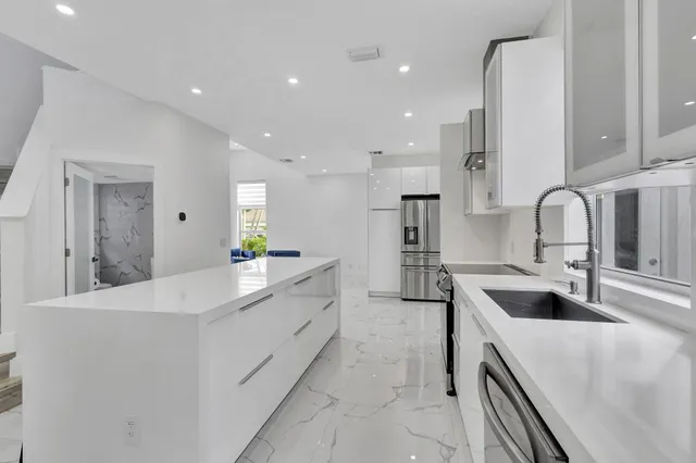 a large white kitchen with wooden floors and stainless steel appliances