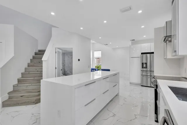 a kitchen with stainless steel appliances a sink stove and white cabinets with wooden floor