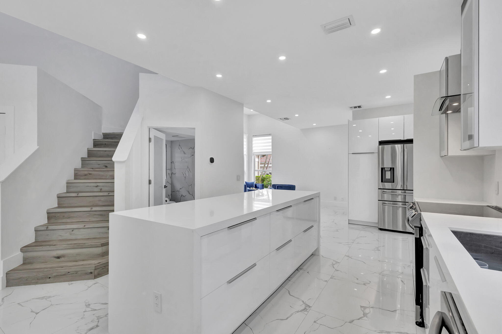 6631 Northwest 25th Avenue Boca Raton, FL 33496 - Photo 12 of 59 a large white kitchen with wooden floors and stainless steel appliances