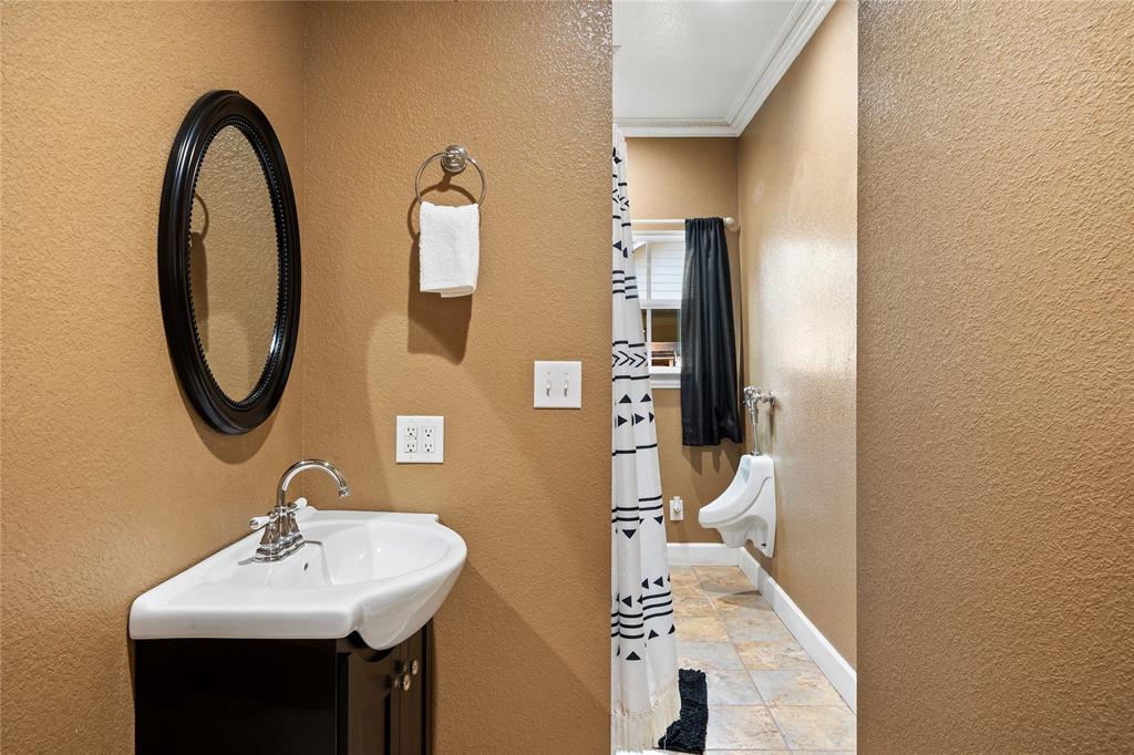 202 North Kickapoo Street Lipan, TX 76462 - Photo 9 of 38 Corner pedestal sink with chrome faucet, black vanity, and oval framed mirror