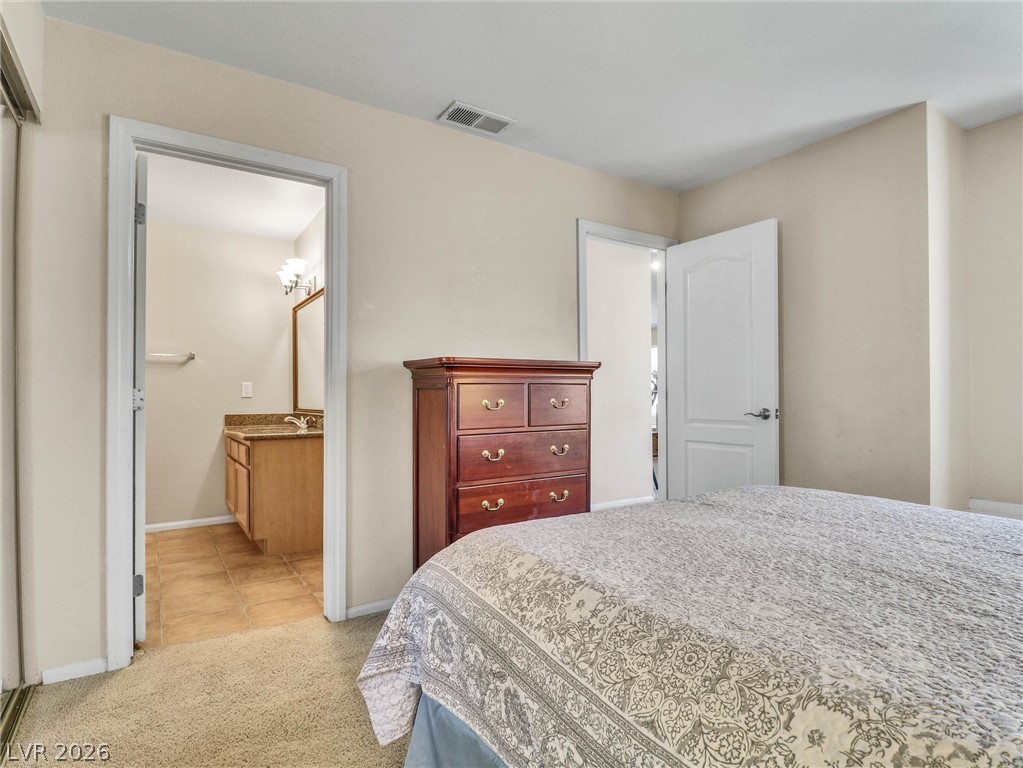 3145 East Flamingo Road, Unit 2129 Las Vegas, NV 89121 - Photo 24 of 43 A well-lit bedroom features plush carpeting and an adjoining full bathroom.