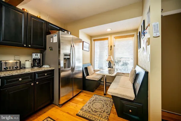 a living room with stainless steel appliances furniture a refrigerator and a kitchen view