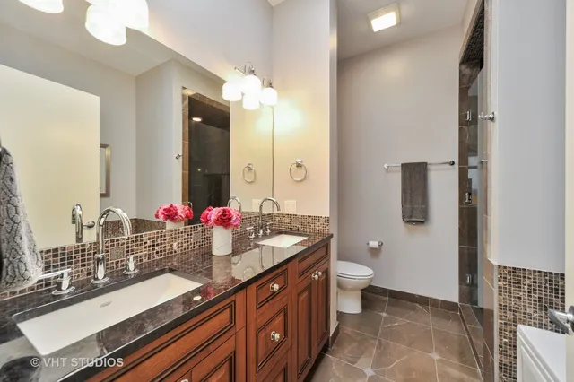 a bathroom with a double vanity sink toilet and mirror