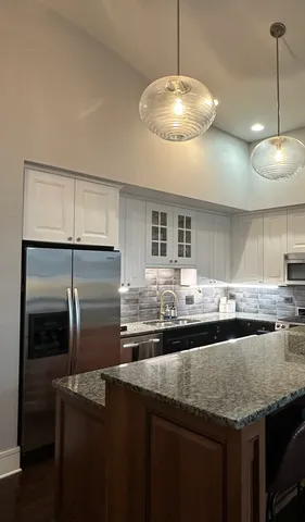 a kitchen with stainless steel appliances granite countertop a sink and a refrigerator