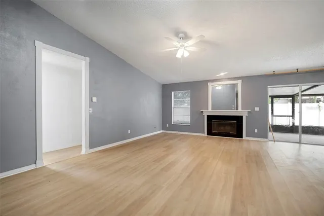 an empty room with windows fireplace and wooden floor