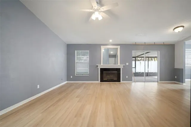 an empty room with windows fireplace and fans