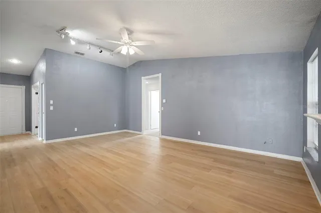 a view of an empty room with glass door and chandelier fan