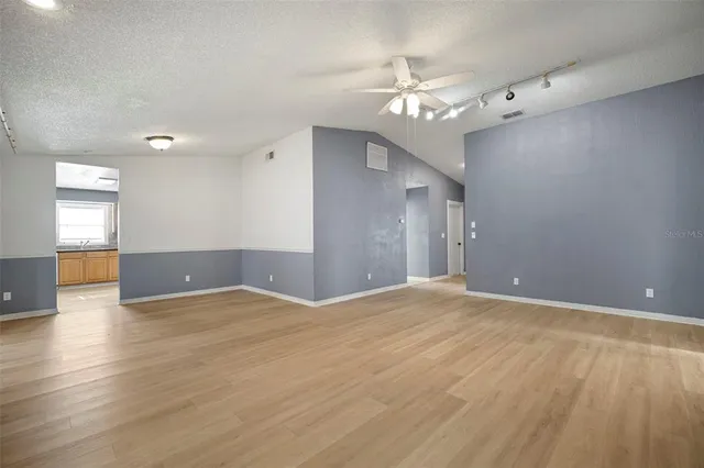 a view of an empty room with wooden floor and a fireplace