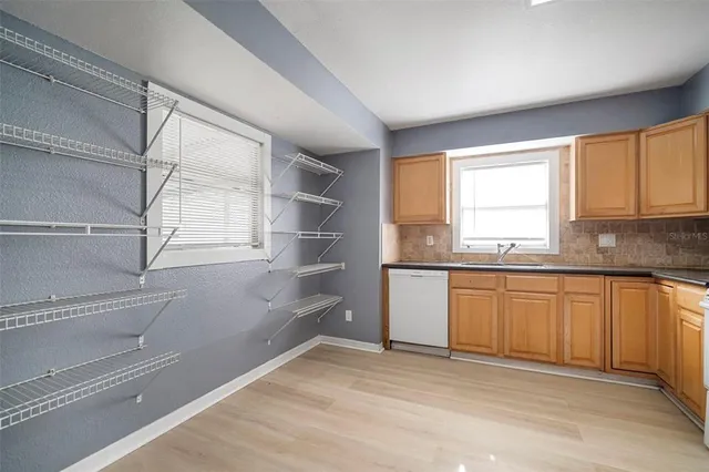 a kitchen with stainless steel appliances granite countertop a stove a sink and white cabinets with wooden floor