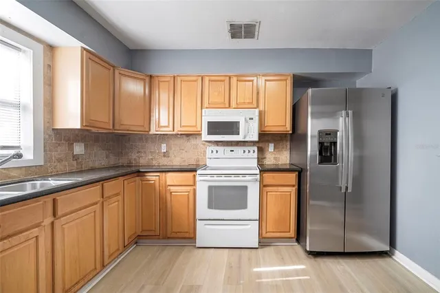a kitchen with stainless steel appliances granite countertop a refrigerator and a stove top oven