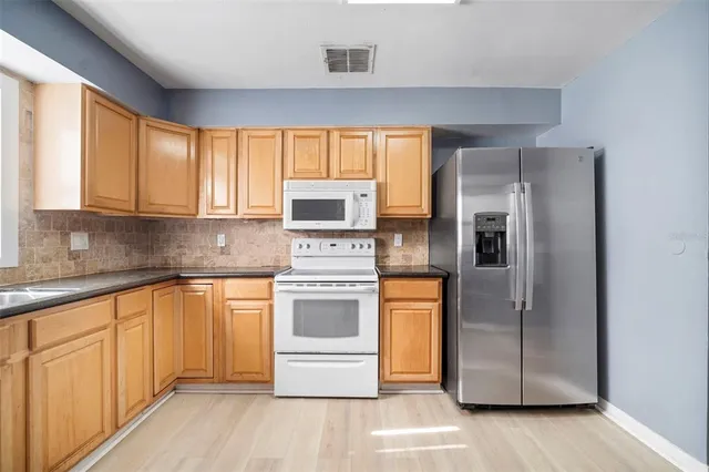 a kitchen with stainless steel appliances granite countertop a refrigerator stove and sink