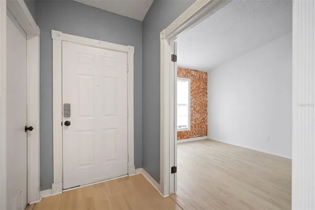 a view of an empty room with wooden floor and a window