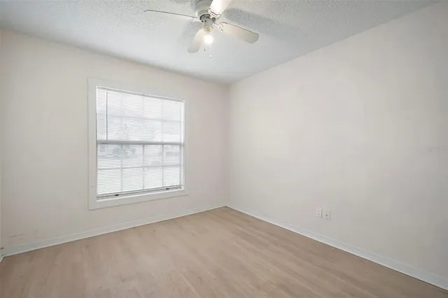 an empty room with chandelier fan and windows
