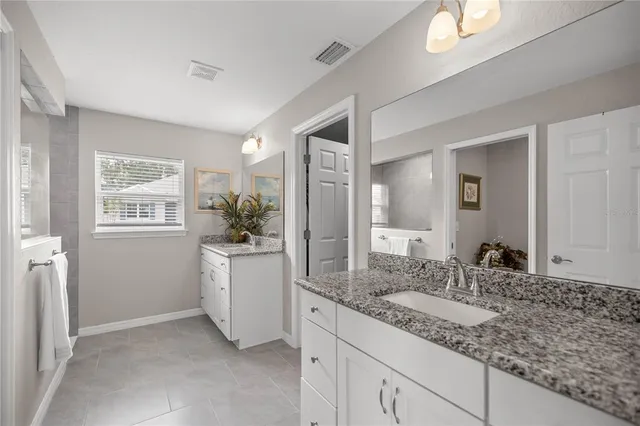 a bathroom with a granite countertop sink mirror and window