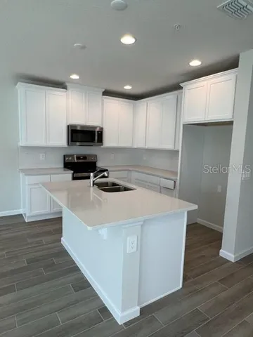 a kitchen with kitchen island a sink a stove a refrigerator and white cabinets